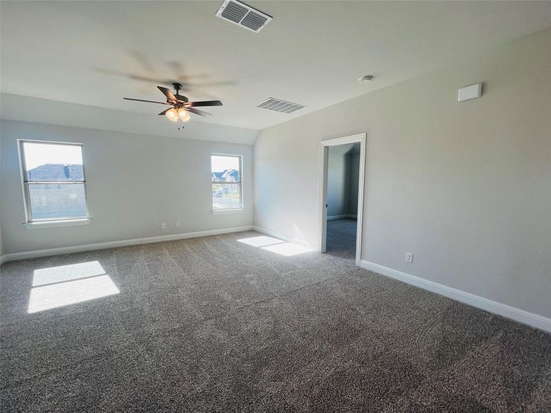 Carpeted spare room featuring baseboards and ceiling fan