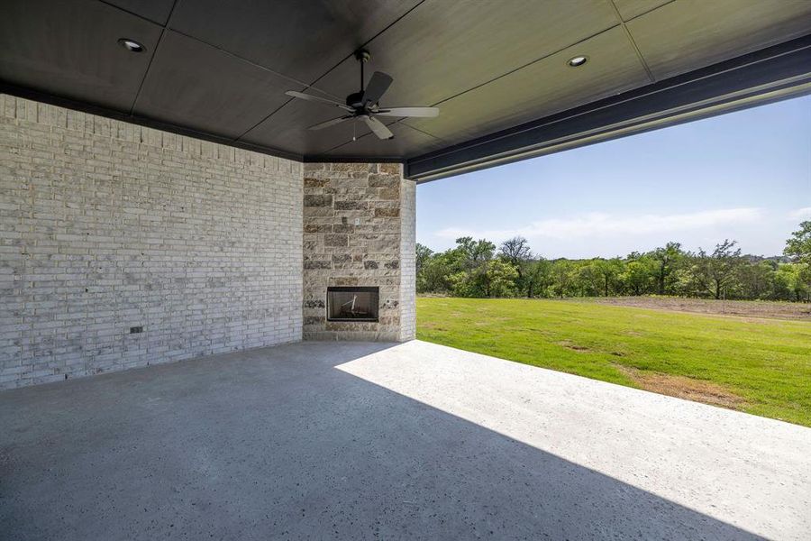 View of patio featuring ceiling fan and an outdoor stone fireplace