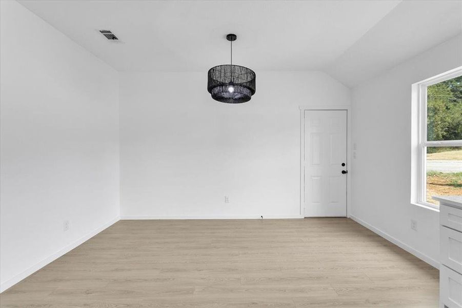 Spare room with plenty of natural light, lofted ceiling, and light hardwood / wood-style flooring