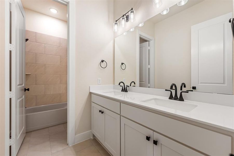 Bathroom with double vanity,  shower combination, and light tile patterned flooring