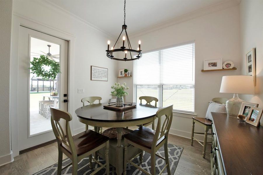 Dining room with ornamental molding, wood finished floors, and a chandelier