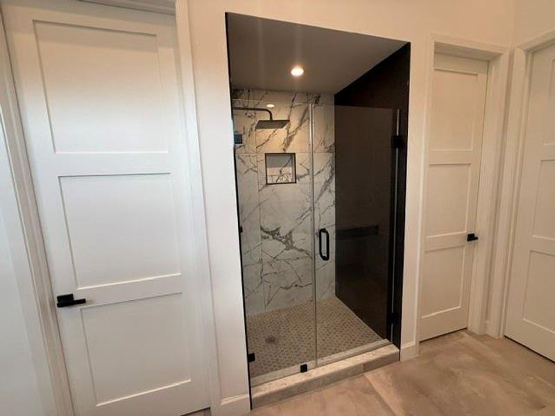Luxurious walk-in shower in the primary bath featuring elegant tile and a modern design.
