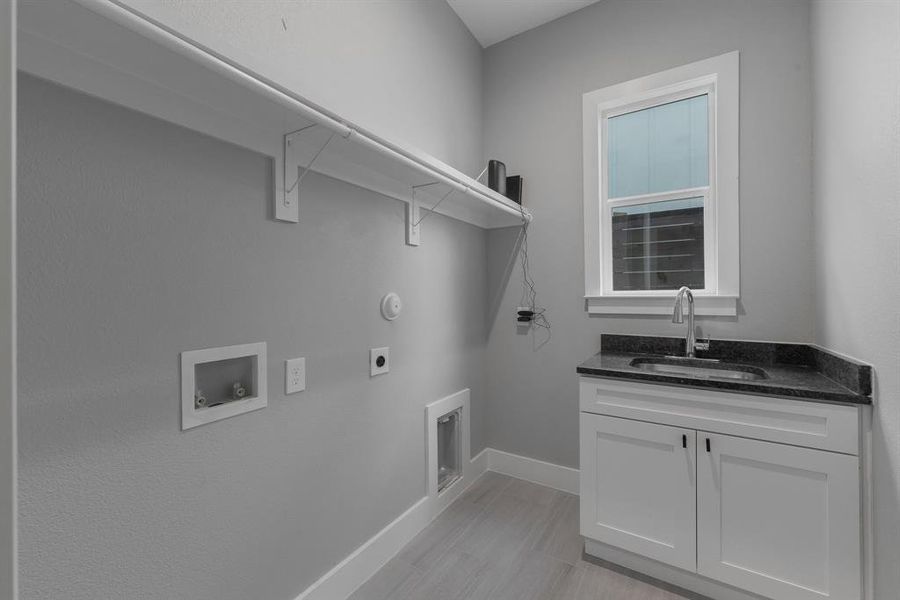 Laundry area featuring baseboards, hookup for a washing machine, cabinet space, hookup for an electric dryer, and a sink