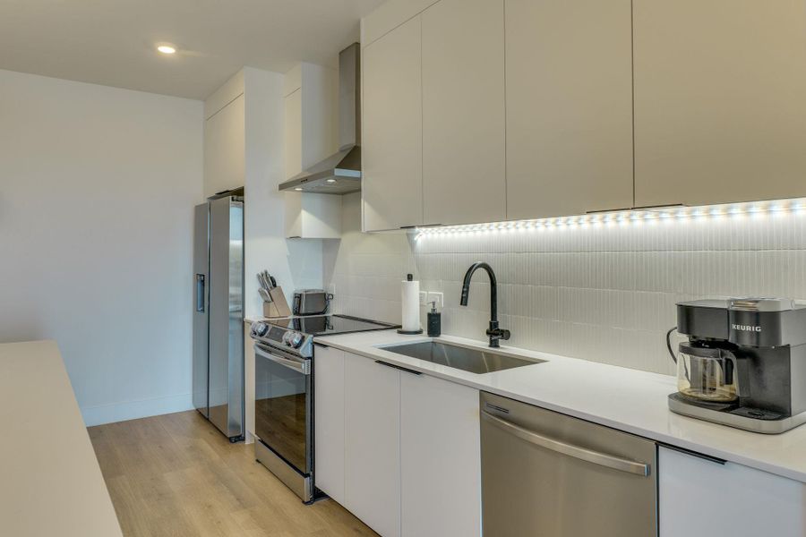 The kitchen features light-toned cabinetry, stainless steel appliances, and a light-colored countertop