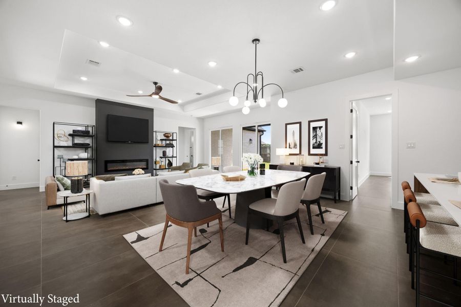 This modern living and dining area features an open floor plan with sleek tile flooring and recessed lighting. It includes a cozy seating area with a fireplace and TV, a stylish dining table, and a breakfast bar. The space is bright and airy, with large windows and contemporary décor.