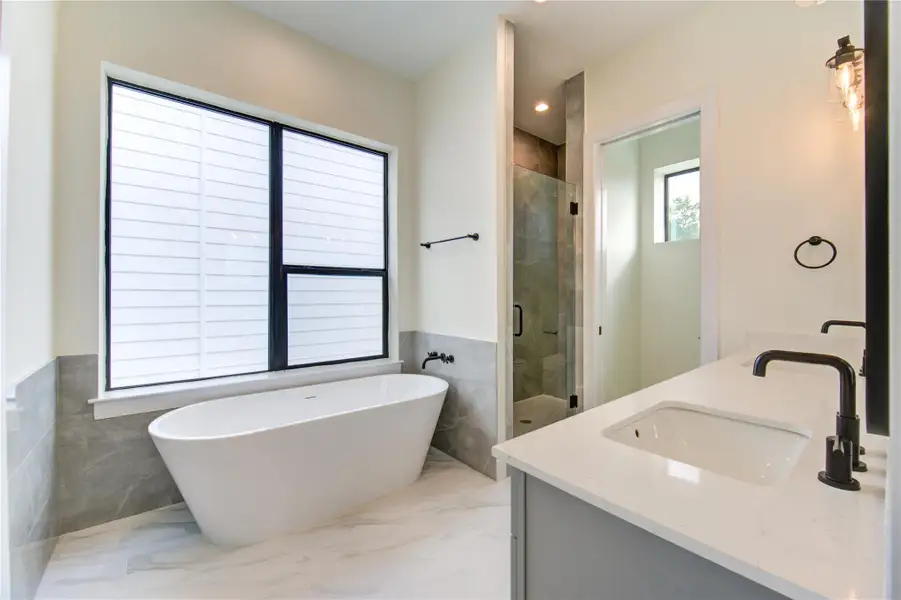Luxurious en suite featuring a sleek freestanding tub, walk-in shower, and elegant double vanity. Luxurious en suite featuring a sleek freestanding tub, walk-in shower, and elegant double vanity.