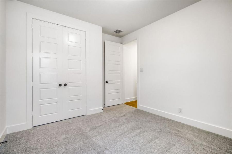Unfurnished bedroom with light colored carpet and a closet