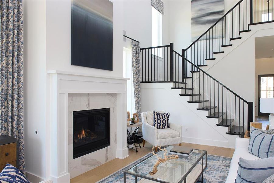 Living room with wood finished floors, a high ceiling, a fireplace, and stairway