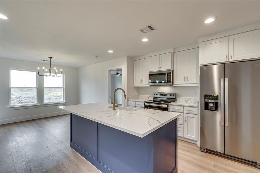 Kitchen featuring light stone counters, visible vents, white cabinetry, appliances with stainless steel finishes, and light wood-type flooring