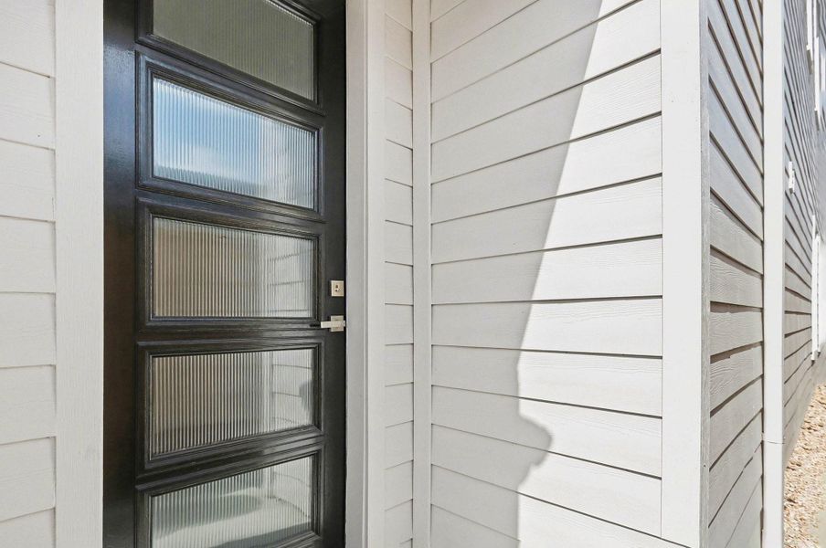 Modern glass-panel front door welcomes you with style and natural light.