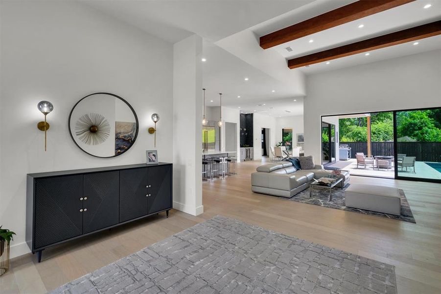 Living room with a towering ceiling, beamed ceiling, and light wood-type flooring