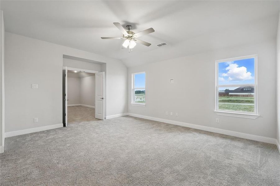 Unfurnished bedroom featuring carpet, vaulted ceiling, baseboards, and a ceiling fan
