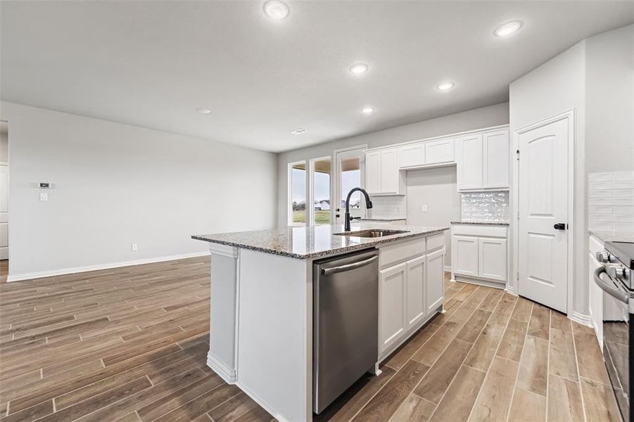 Kitchen with wood finish floors, appliances with stainless steel finishes, white cabinetry, light stone countertops, and recessed lighting Kitchen with wood finish floors, appliances with stainless steel finishes, white cabinetry, light stone countertops, and recessed lighting