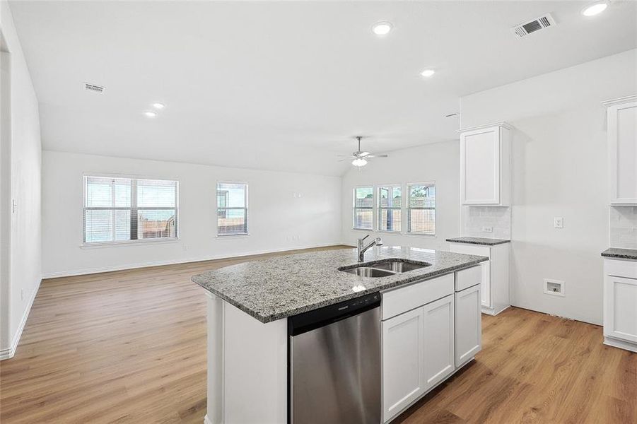 Kitchen with ceiling fan, light hardwood / wood-style flooring, stainless steel dishwasher, backsplash, and sink