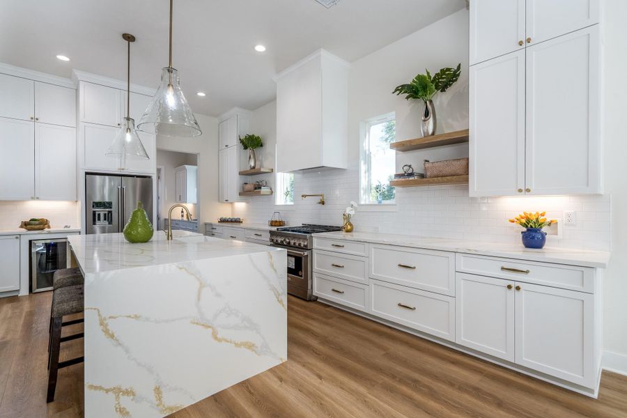 Modern kitchen with white cabinetry, subway tile backsplash, and stainless-steel appliances including gas range and fridge. Modern kitchen with white cabinetry, subway tile backsplash, and stainless-steel appliances including gas range and fridge.