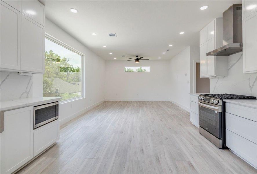 Kitchen with range hood, appliances with stainless steel finishes, a ceiling fan, backsplash, and white cabinets