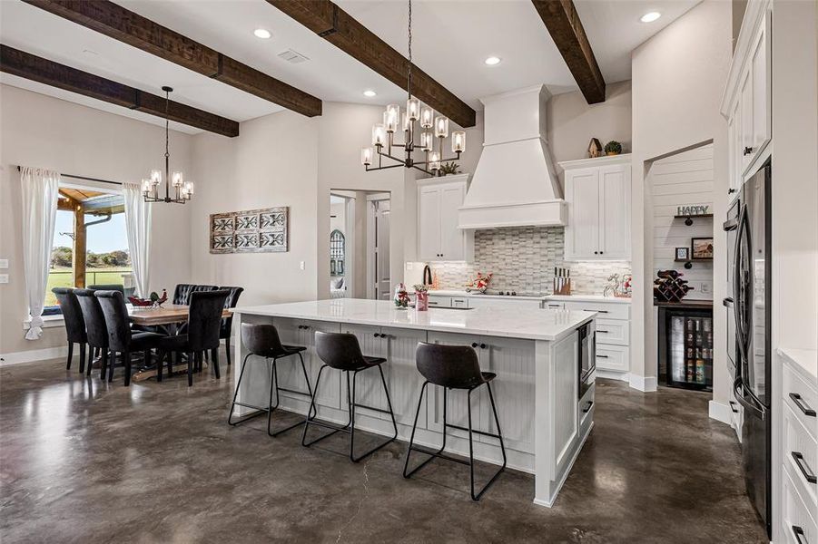 Kitchen with a chandelier, concrete floors, backsplash, beam ceiling, and recessed lighting Kitchen with a chandelier, concrete floors, backsplash, beam ceiling, and recessed lighting