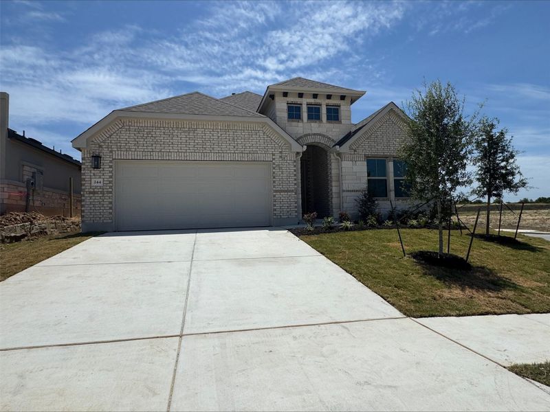 French provincial home with brick siding, a garage, driveway, a front lawn, and a shingled roof French provincial home with brick siding, a garage, driveway, a front lawn, and a shingled roof