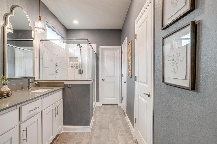 Bathroom with a textured wall, a stall shower, wood finished floors, and vanity