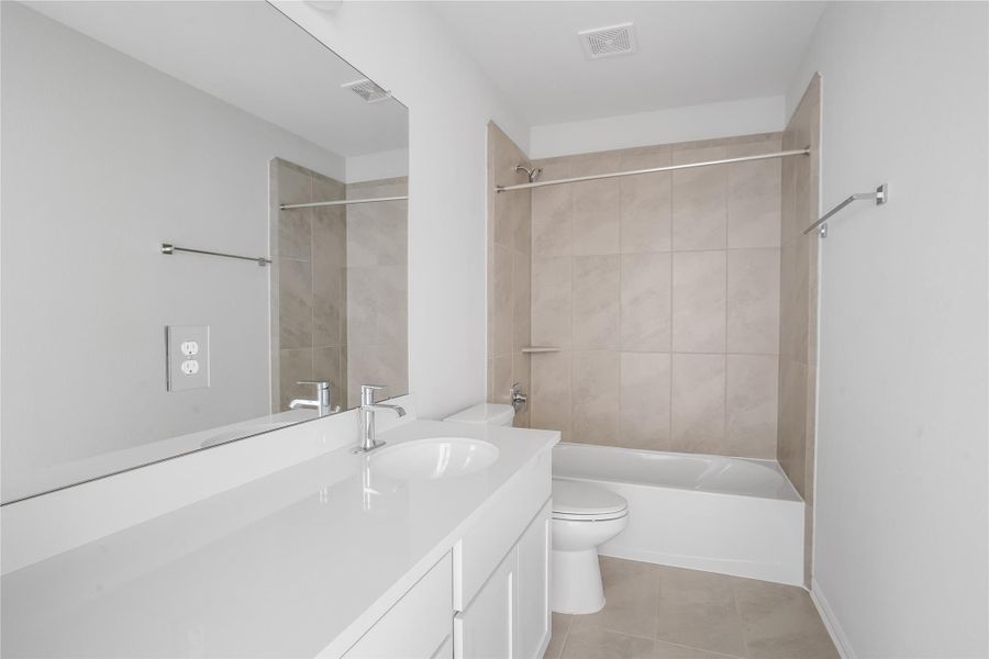 Secondary bathroom features tile floors, spacious countertop, and a tub and shower combo with tile surround.