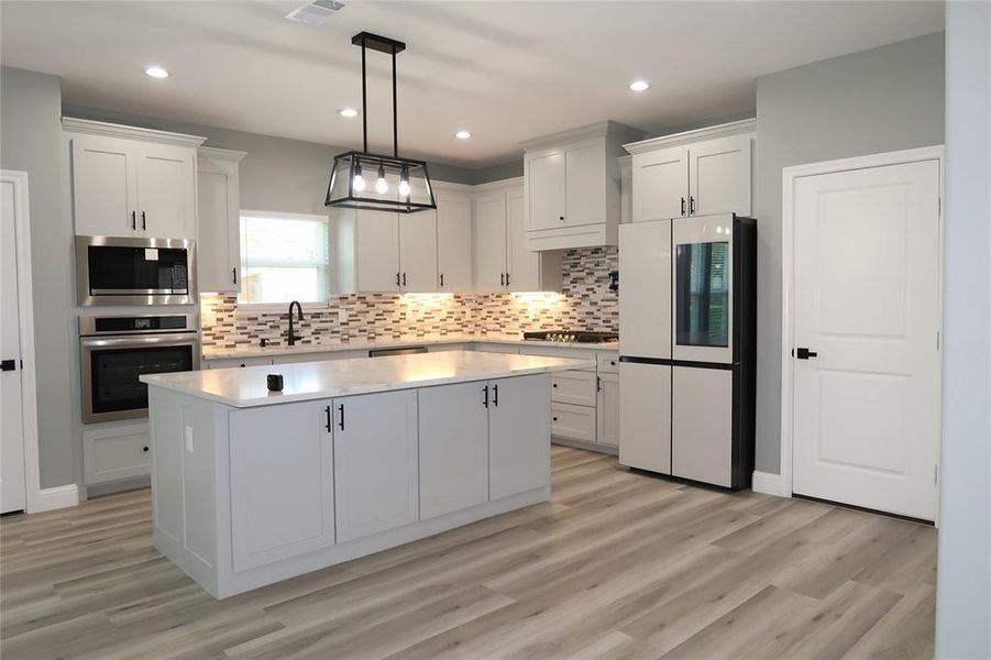 Kitchen with appliances with stainless steel finishes, decorative light fixtures, white cabinetry, decorative backsplash, and recessed lighting