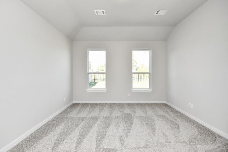 Escape and relax in the exquisite primary suite, a haven to unwind after a long day. The spacious room, located on first floor, boasts plush carpeting, soothing paint tones, high ceilings, and expansive windows adorned with privacy blinds. Sample photo of completed home with similar floor plan. Actual colors and selections may vary.