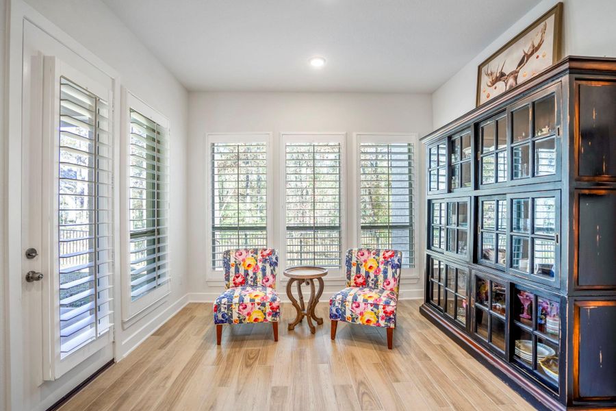 This bright breakfast room features large windows with plantation shutters, allowing plenty of natural light and the light wood flooring enhances the airy feel. Through that door is your backyard retreat.