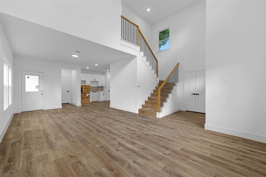 Unfurnished living room featuring light hardwood / wood-style flooring, a wealth of natural light, and a high ceiling