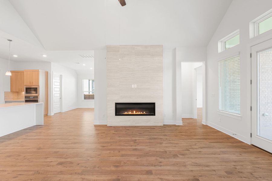An inviting open-concept living area features rich wood flooring and a sleek fireplace centerpiece.