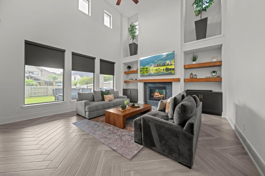 Spacious living room with two-story ceilings, oversized windows, and a fireplace framed by custom floating shelves. A centerpiece for gatherings. Spacious living room with two-story ceilings, oversized windows, and a fireplace framed by custom floating shelves. A centerpiece for gatherings.