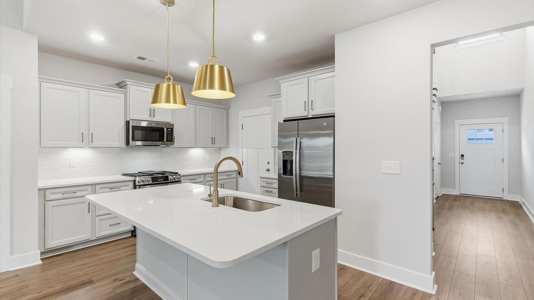 Exceptional kitchen featuring a spacious island, eye-catching pendant lights, and modern finishes at Village at Midway Exceptional kitchen featuring a spacious island, eye-catching pendant lights, and modern finishes at Village at Midway