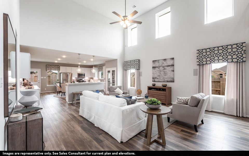 Living area featuring dark wood-type flooring, ceiling fan, healthy amount of natural light, and a high ceiling