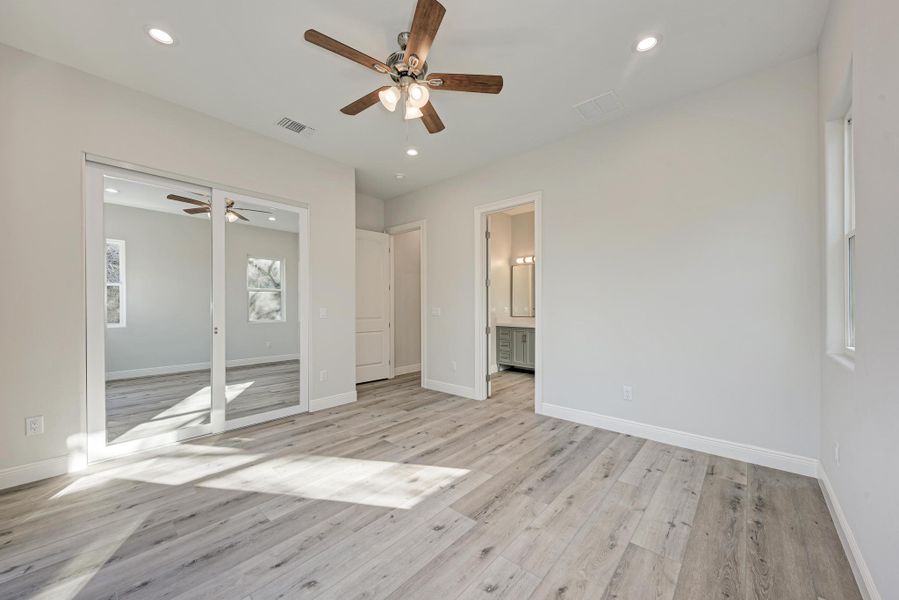 Unfurnished bedroom featuring recessed lighting, light wood-style flooring, ceiling fan, a closet, and connected bathroom