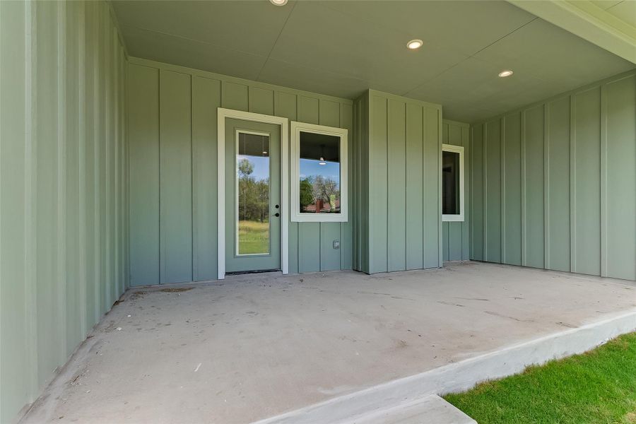 View of exterior entry with a patio and board and batten siding