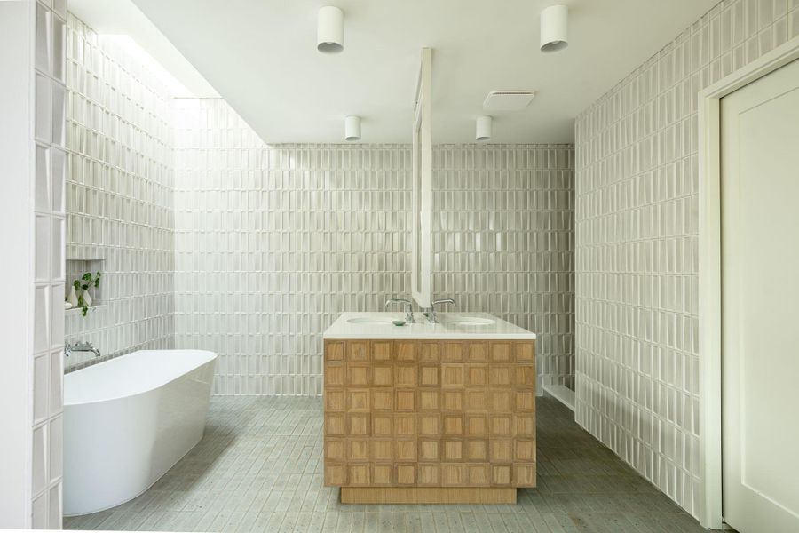 Full bathroom with tile walls, a freestanding bath, vanity, and light tile patterned flooring