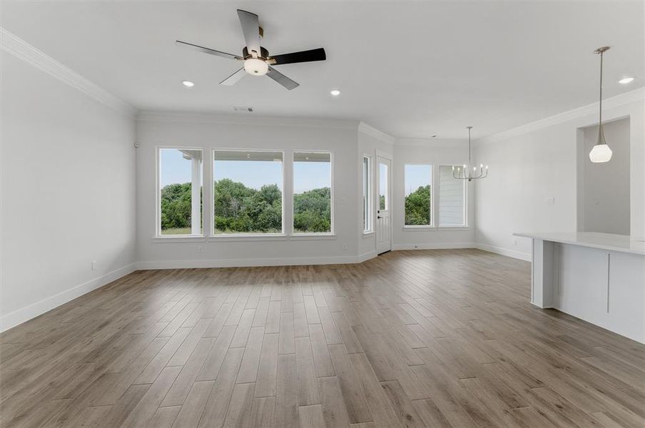 Spacious interior showcasing wood-finish flooring, recessed lighting, and crown molding