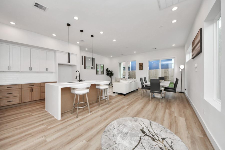 Discover modern elegance in this open-concept living space, featuring a stunning waterfall kitchen island that seamlessly blends style and functionality.