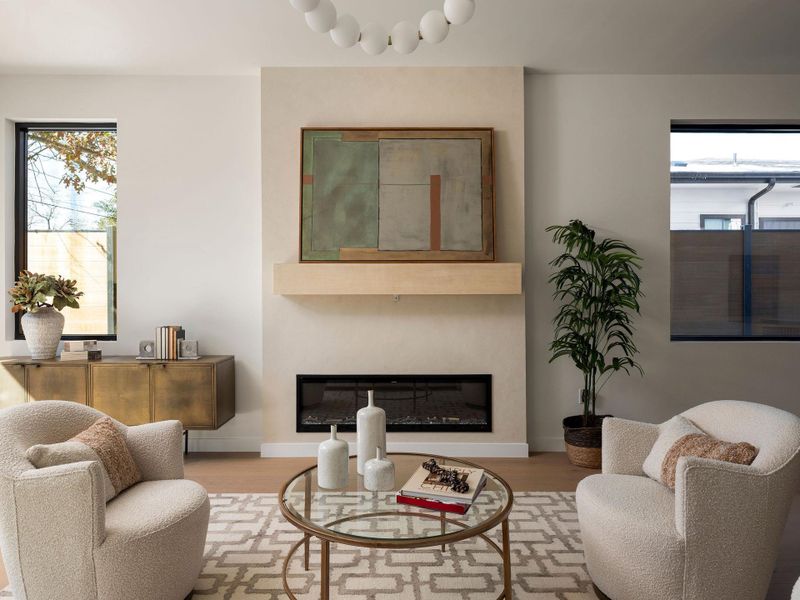 Living area with healthy amount of natural light, a glass covered fireplace, and wood finished floors