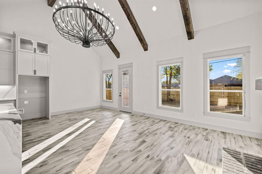 Unfurnished living room featuring beamed ceiling, high vaulted ceiling, a chandelier, light wood-style floors, and recessed lighting Unfurnished living room featuring beamed ceiling, high vaulted ceiling, a chandelier, light wood-style floors, and recessed lighting