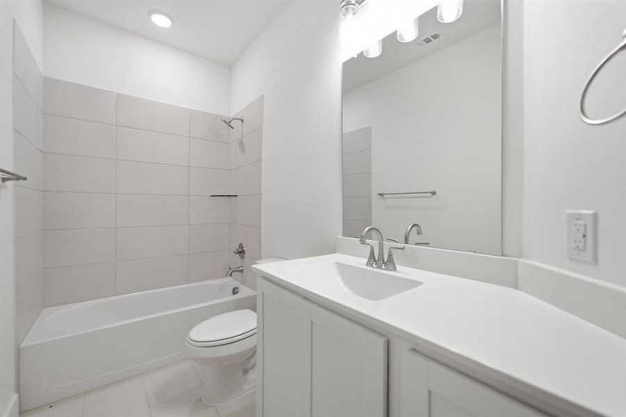 Bright bathroom featuring a single vanity with a white countertop, undermount sink, and a large mirror