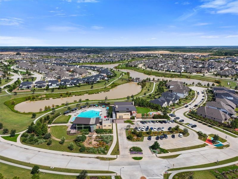 This photo captures the vibrant lifestyle offered at Elyson, with the community amenity center overlooking picturesque lakes. The close proximity of the pool, splash pad, dog park, and dinosaur digging area provides endless entertainment options for families.