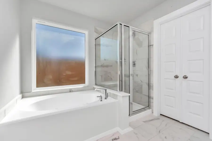 This additional view of the primary bath features a walk-in shower with the tile surround and separate garden tub perfect for soaking after a long day. Sample photo of completed home with similar floor plan. As-built interior colors and selections may vary. This additional view of the primary bath features a walk-in shower with the tile surround and separate garden tub perfect for soaking after a long day. Sample photo of completed home with similar floor plan. As-built interior colors and selections may vary.