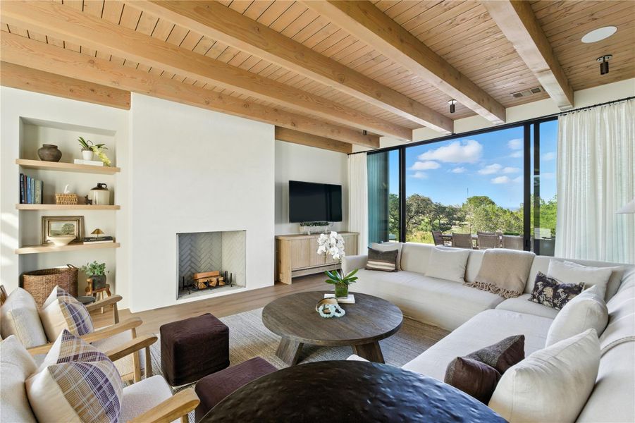 Living area featuring built in shelves, wood finished floors, a wood ceiling with exposed beams, and a fireplace