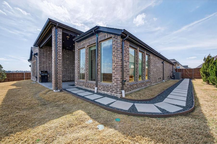 View of property exterior with brick siding, a fenced backyard, and a patio View of property exterior with brick siding, a fenced backyard, and a patio