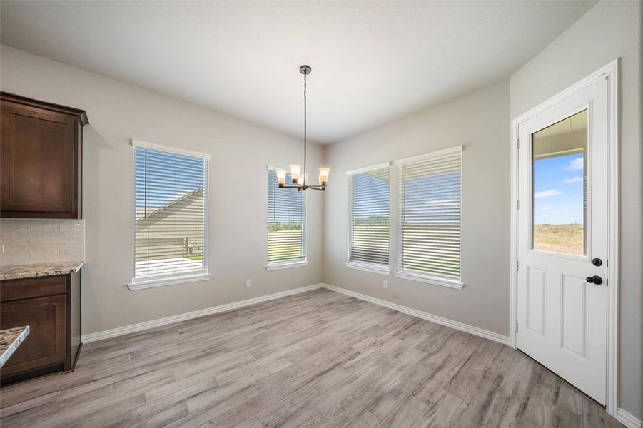 Unfurnished dining area with light wood-type flooring and a chandelier Unfurnished dining area with light wood-type flooring and a chandelier