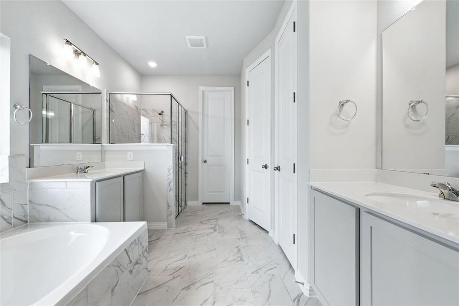 Full bathroom featuring a stall shower, marble finish flooring, two vanities, and a garden tub Full bathroom featuring a stall shower, marble finish flooring, two vanities, and a garden tub