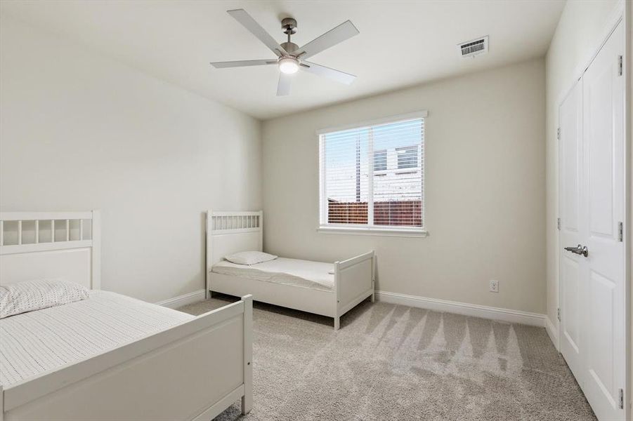 Carpeted room featuring a ceiling fan with integrated lighting, a window with horizontal blinds, and a double-door closet