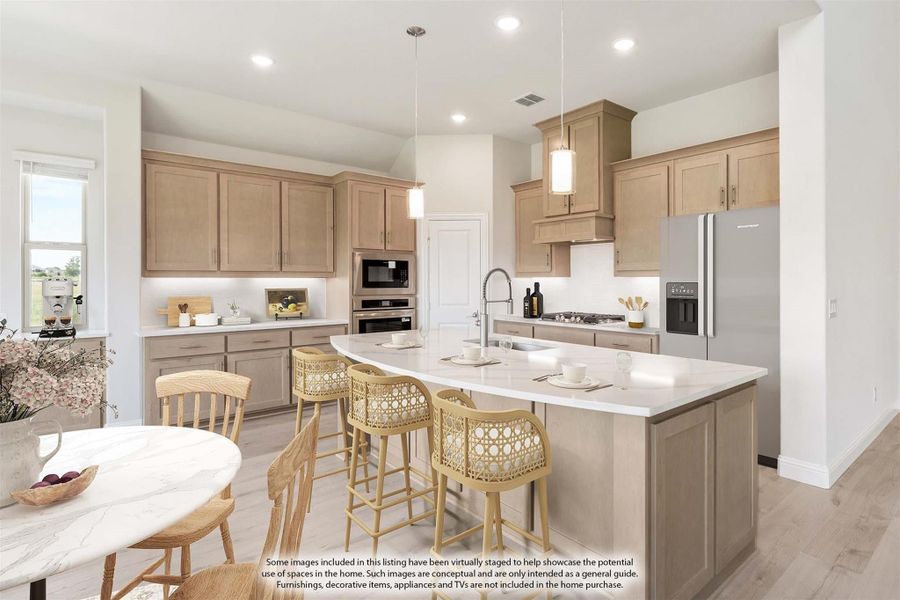Kitchen with light wood cabinets, large island with seating, stainless steel appliances, and pendant lights