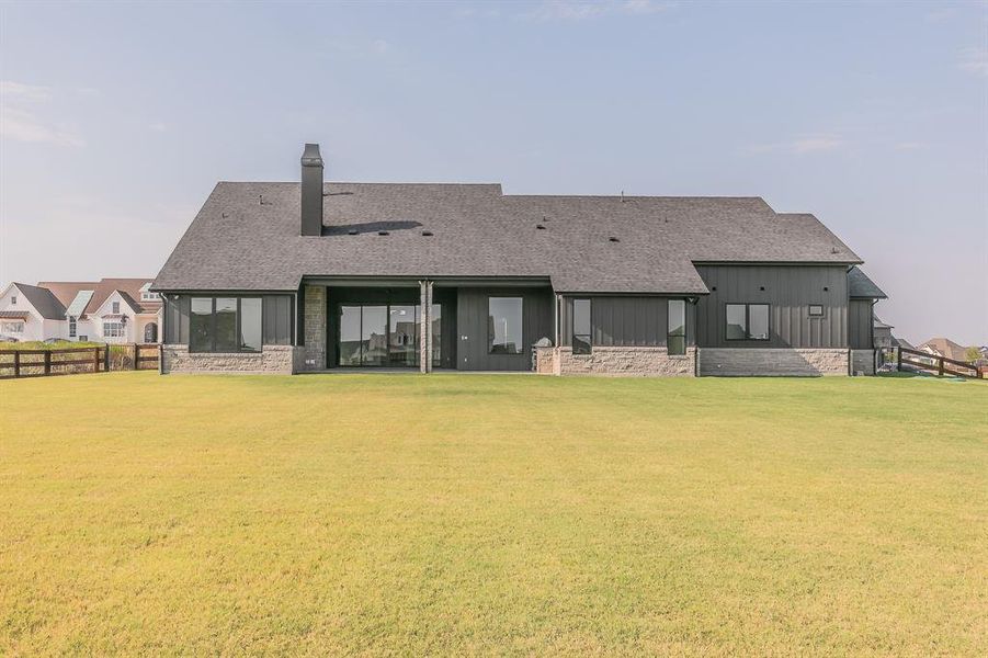 Rear view of property featuring board and batten siding, a patio, a chimney, and a shingled roof