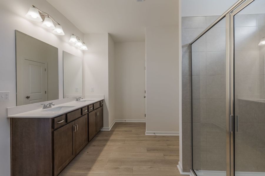 Primary en suite bathroom with double vanities and large tiled walk-in shower.